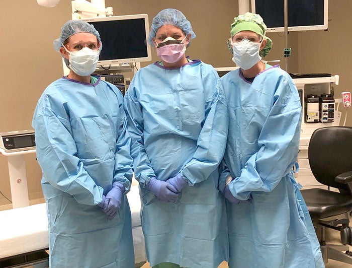 three nurses standing together with full gear on