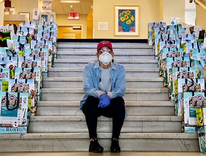 Staff member sitting on stairs between bags of to distribute during the COVID-19 pandemic
