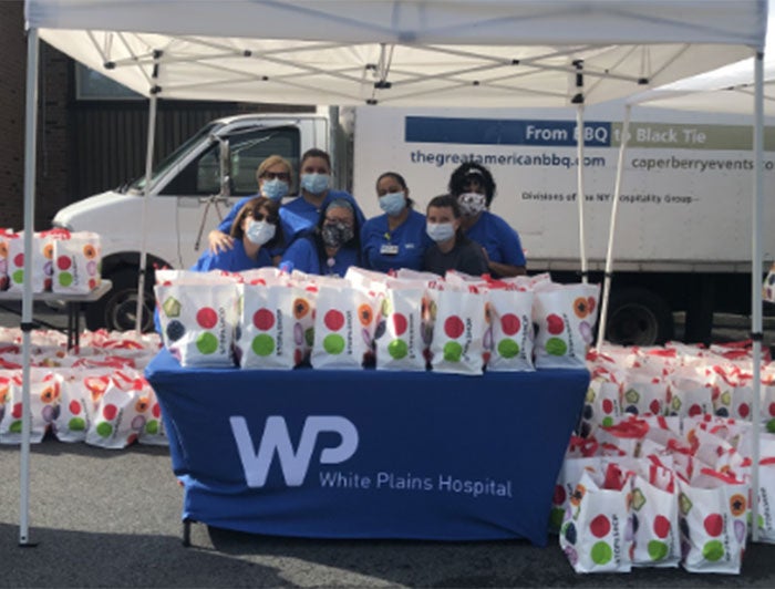 White Plains Hospital volunteers stand with bags of food to be distributed