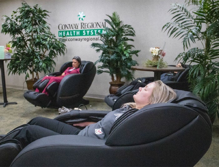 2 staff members taking a break, relaxing in massage chairs - Conway (Arkansas) Regional Health System