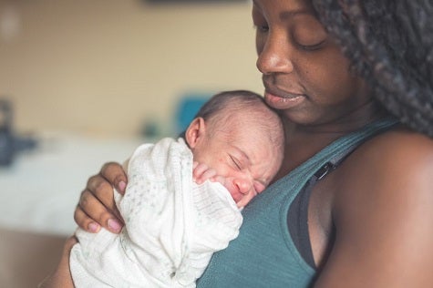 Maternal and Child Health. A mother holds her newborn baby in a hospital room.