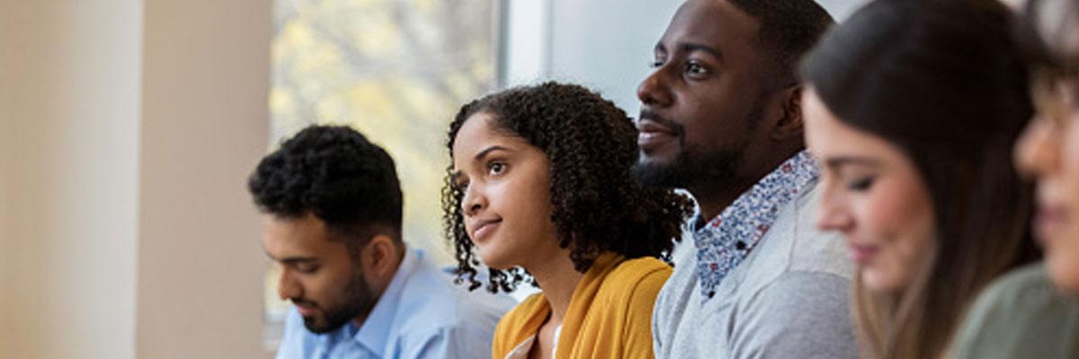 Diverse young professionals lin profile looking off to an off-camera speaker in a seminar